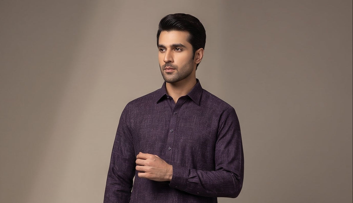 A man wearing a dark purple textured long-sleeve kurta, standing against a neutral beige studio background.